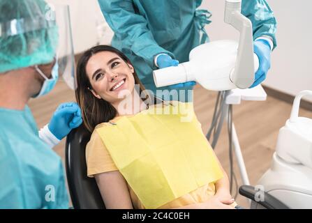 Dentista uomo che opera giovane donna sorridente in clinica dentale - concetto di assistenza sanitaria orale Foto Stock