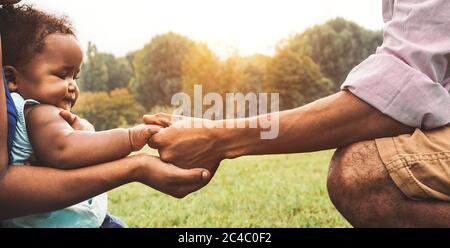 Felice famiglia africana che si diverte insieme nel parco pubblico - il padre nero e la madre che tiene la mano con la loro figlia Foto Stock