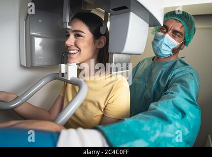 Paziente giovane donna in piedi in macchina radiologica - dentista che fa radiografia dentale panoramica - concetto sanitario Foto Stock