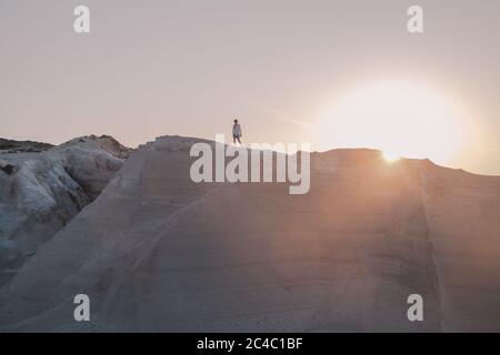 Uomo alla scoperta della spiaggia di Sarakiniko a Milos, Grecia al tramonto Foto Stock