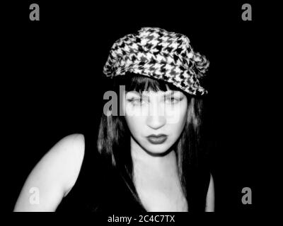 femmina con capelli lunghi, diritti, scuri, stile anni '60, o forse stile anni '90, con un cappello a denti hounds. Occhi molto impressionanti Foto Stock