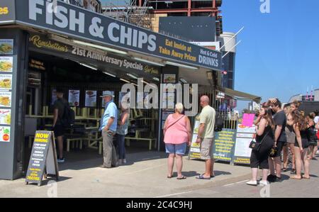 Skegness, Regno Unito. 25 Giugno 2020. La gente coda fuori da un pesce e patatine takeaway il giorno più caldo dell'anno. La gente si dirige alla spiaggia nella popolare località balneare di Skegness come l'Inghilterra registra il suo giorno più caldo dell'anno con temperature a 30 gradi Celsius. Credit: SOPA Images Limited/Alamy Live News Foto Stock