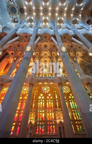 Su un lato della Sagrada Familia le vetrate si avvantaggiano del sole che tramonta, con colori caldi rossi, arance e gialli. Foto Stock