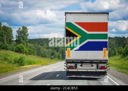 Un camion con la bandiera nazionale della Repubblica sudafricana raffigurata sulla porta posteriore trasporta le merci in un altro paese lungo la strada. Concetto di ESP Foto Stock