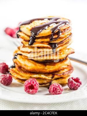 Deliziosi frittelle al formaggio di cottage con lampone fresco e un sorrup al cioccolato. Frittelle cagliate. Foto Stock