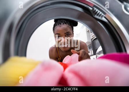 Donna che usa il sapone di riempimento della lavatrice guardando dentro Foto Stock