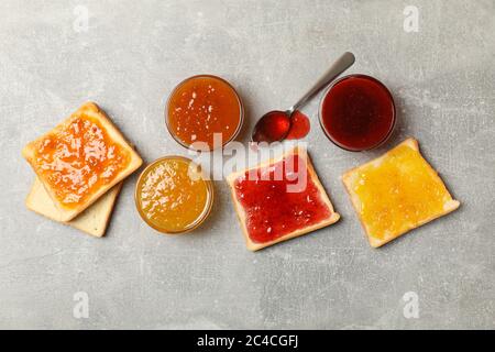 Ciotole e toast con marmellata su sfondo grigio, vista dall'alto Foto Stock