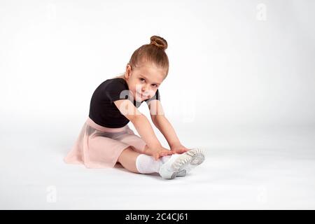 Bambina che fa esercizi di stretching e ginnastica su sfondo bianco Foto Stock