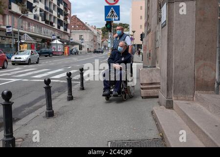 Belgrado, Serbia 18 giugno 2020: Un uomo in sedia a rotelle e il suo compagno in attesa di attraversare la strada Foto Stock