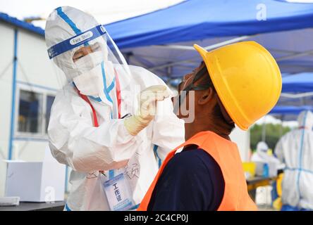 Pechino, Cina. 26 Giugno 2020. Un membro del personale medico (L) raccoglie un campione di tampone faringeo di un lavoratore presso una struttura di test dell'acido nucleico COVID-19, istituita temporaneamente in un sito di costruzione nel distretto di Haidian a Pechino, capitale della Cina, il 26 giugno 2020. Venerdì più di 1,750 operai edili a Pechino hanno ricevuto test COVID-19 sugli acidi nucleici. Credit: Ren Chao/Xinhua/Alamy Live News Foto Stock