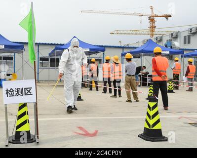 Pechino, Cina. 26 Giugno 2020. Un membro del personale (L, anteriore) disinfetta una struttura di test per gli acidi nucleici COVID-19, istituita temporaneamente in un cantiere nel distretto di Haidian a Pechino, capitale della Cina, il 26 giugno 2020. Venerdì più di 1,750 operai edili a Pechino hanno ricevuto test COVID-19 sugli acidi nucleici. Credit: Ren Chao/Xinhua/Alamy Live News Foto Stock