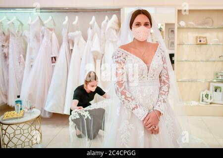 I rivestimenti del viso sono indossati dalla sposa per essere Jessica Letheren e consulente nuziale Felicity Grey durante un appuntamento di vestimento a Allison Jayne Bridalwear a Clifton, Bristol, che si è riaperto in seguito all'abolizione delle restrizioni di blocco del coronavirus, con misure adottate per impedire la diffusione del coronavirus durante l'allestimento degli abiti delle spose. Foto Stock