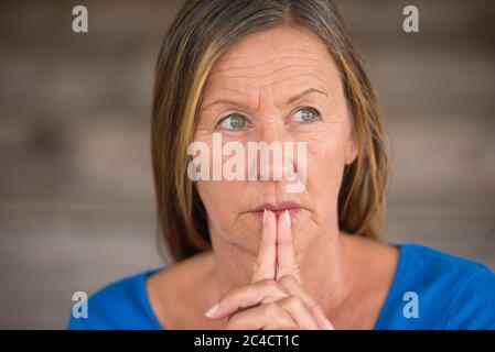 Portrtait attraente religiosa cristiana matura donna pregare con le mani piegate, pensoso, speranzoso, meditante, sfondo sfocato, spazio di copia. Foto Stock