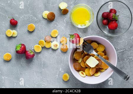 Cibo alla moda - cereali pancake. Un mucchio di mini frittelle di cereali con fragole e yogurt in un boul leggero. Vista dall'alto o in piano. Foto Stock