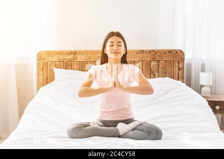 Ragazza rilassante facendo yoga seduta in Lotus posizione a casa Foto Stock