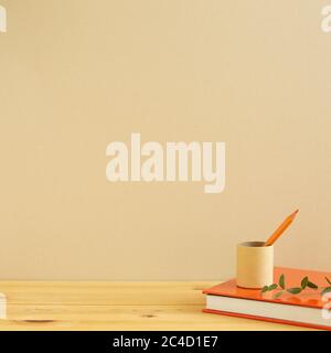 Luogo di lavoro e studio. Libro di note, matita su scrivania in legno con sfondo beige. Spazio per le copie Foto Stock