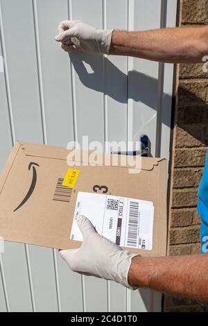 Uomo persona che bussa sulla porta della casa indossare guanti protettivi covid 19 consegna pacchetto Amazon consegna Inghilterra UK Regno Unito Foto Stock