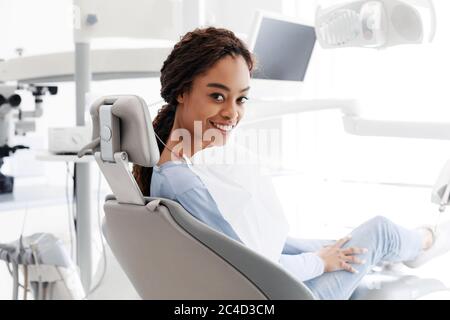 Donna allegra nera seduta in sedia dentista Foto Stock