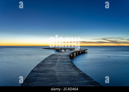 Ponte panoramico sulla riva del mare sotto il tramonto con le nuvole rosee. Foto Stock