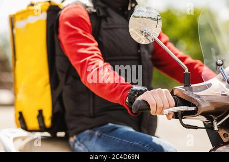 Corriere con zaino giallo che consegna cibo in scooter all'aperto, corto Foto Stock