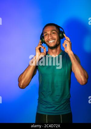 Indossa le cuffie da uomo e ascolta la musica su sfondo blu Foto Stock