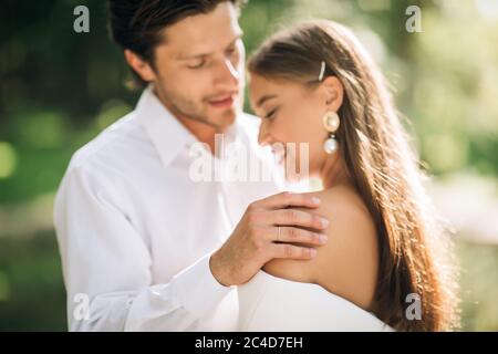 Sposo abbracciando sposa prima di baciare alla cerimonia nuziale esterna Foto Stock