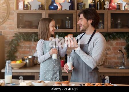 Happy Girl e suo Padre mangiano muffin e bevono latte in cucina Foto Stock