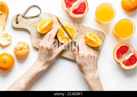 Mani che tagliano gli agrumi per il succo d'arancia Foto Stock