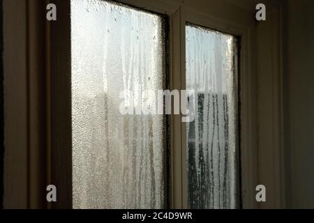 Interno di un vecchio cottage, che mostra la condensa pesante acqua sulle finestre interne durante una mattina inverni. Le cornici in legno sono visibili. Foto Stock