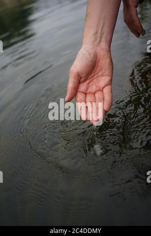 Mani che si tuffano in acqua di fiume Foto Stock