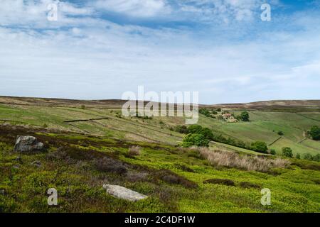 North York Moors con prominenti erpazioni, alberi, campi, erica e erbe sotto il cielo blu e nuvoloso in primavera a Glaisdale, Yorkshire, Regno Unito. Foto Stock