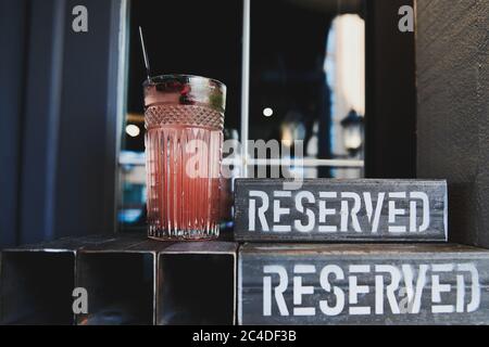 Cocktail di melograno fresco nel ristorante. Rinfrescante limonata nel bel bicchiere. Cartello metallo riservato. Tavolo riservato al bar. Foto Stock