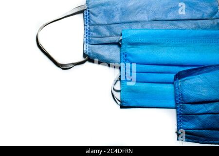 Tre pezzi di maschere chirurgiche sono tenuti uno sopra l'altro su uno sfondo bianco Foto Stock
