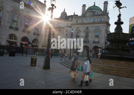 Con altre 149 segnalazioni di morte di Coronavirus nelle ultime 24 ore, portando il numero delle vittime britanniche a 43,320, gli acquirenti camminano sotto la statua di Eros a Piccadilly Circus durante la pandemia di Covid, il 25 giugno 2020, a Londra, Inghilterra. Foto Stock