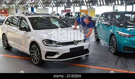 26 giugno 2020, Sassonia, Zwickau: Stefan Schubert (22), tecnico di manutenzione del reparto di assemblaggio finale presso lo stabilimento di Volkswagen Sachsen, ha lucidato l'ultima variante VW Golf accanto al nuovo ID.3 dopo oltre sei milioni di vetture prodotte, l'ultimo motore a combustione ora esce dalla linea di assemblaggio con il veicolo. Questo segna la fine di un'era a Zwickau, una località automobilistica ricca di tradizione. Già in novembre, VW aveva iniziato la produzione in serie del tutto elettrico ID.3 presso il suo stabilimento in Sassonia. La produzione deve essere gradualmente aumentata da 1500 veicoli al giorno. L'auto elettrica deve essere lau Foto Stock