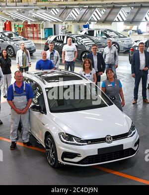 26 giugno 2020, Sassonia, Zwickau: I dipendenti dello stabilimento di Volkswagen Sachsen stanno terminando la linea intorno a una variante VW Golf. Dopo oltre sei milioni di automobili prodotte, l'ultimo motore a combustione sta ora disallineando la linea di assemblaggio. Questo segna la fine di un'epoca a Zwickau, un luogo immerso nella tradizione. VW aveva già avviato la produzione in serie del tutto elettrico ID.3 presso il suo stabilimento in Sassonia nel mese di novembre. La produzione deve essere gradualmente aumentata da 1500 veicoli al giorno. L'auto elettrica sarà lanciata sul mercato a settembre. Foto: Hendrik Schmidt/dpa-Zentralbild/dpa Foto Stock