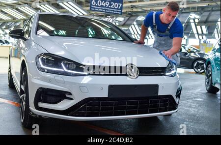 26 giugno 2020, Sassonia, Zwickau: Stefan Schubert (22), tecnico di manutenzione del reparto di assemblaggio finale presso lo stabilimento di Volkswagen Sachsen, ha lucidato l'ultima variante VW Golf accanto al nuovo ID.3 dopo oltre sei milioni di vetture prodotte, l'ultimo motore a combustione ora esce dalla linea di assemblaggio con il veicolo. Questo segna la fine di un'era a Zwickau, una località automobilistica ricca di tradizione. Già in novembre, VW aveva iniziato la produzione in serie del tutto elettrico ID.3 presso il suo stabilimento in Sassonia. La produzione deve essere gradualmente aumentata da 1500 veicoli al giorno. L'auto elettrica deve essere lau Foto Stock