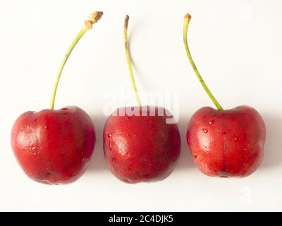 Tre ciliegie fresche mature isogallate su sfondo bianco Foto Stock