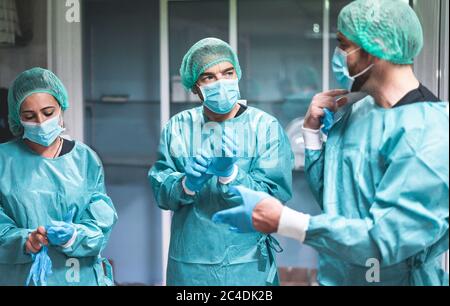 Medici e infermieri si preparano a lavorare in ospedale per l'intervento chirurgico durante l'epidemia di coronavirus pandemic - operatori medici che si vestono all'interno c Foto Stock