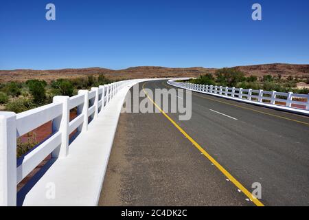 Una strada appena asfaltata con recinzione bianca nel deserto del Namib, Namibia, Africa Foto Stock