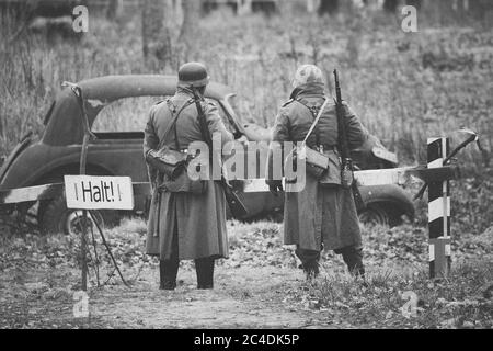 I Re-enactor non identificati vestiti come soldato tedesco della fanteria Wehrmacht alla seconda guerra mondiale sono in pattuglia in campo autunnale. Foto Stock