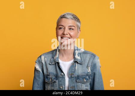 Ritratto di affascinante donna matura in elegante giacca denim su sfondo giallo Foto Stock