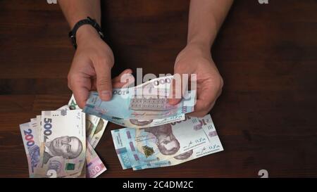 L'uomo considera i nuovi soldi di carta ucraini. Mani maschili che tengono il pacco di banconote valore nominale 1000 hryvnia. Primo piano Foto Stock