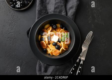 Piccola frittella fatta in casa con mirtillo su nero. Vista dall'alto. Gustosa colazione alla moda. Foto Stock