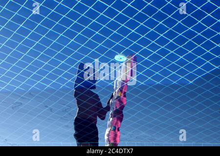 Giovane uomo che tiene un Float Pink Pool riflesso nel Acqua della piscina Foto Stock