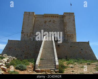 COMINO, MALTA - 27 aprile 2014: Torre di Santa Marija, costruita dai Cavalieri Ordine di San Giovanni, sulle scogliere e il mare blu sull'isola di Comino, Malta. PRI Foto Stock