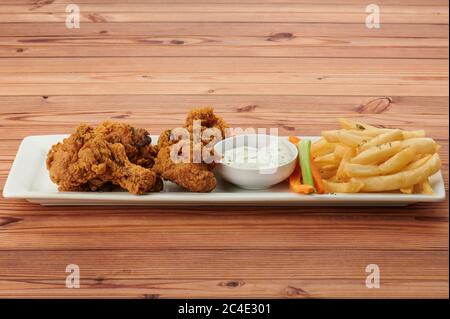 Pollo fritto con patatine fritte su tavolo di legno Foto Stock