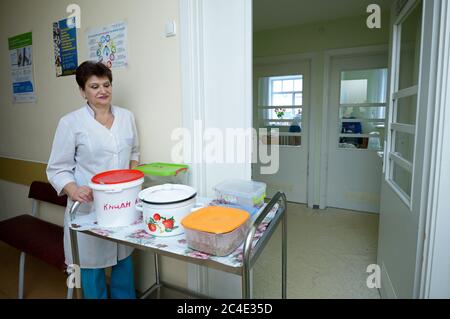 In ospedale. Infermiere in camici da laboratorio tirando un carrello con cibo in pentole per i pazienti Foto Stock