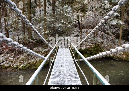 Ponte a catena innevato sul fiume Hornad nel Parco Nazionale del Paradiso Slovacco, Slovacchia Foto Stock