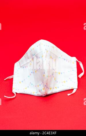 Maschera facciale in tessuto DIY con bandiere triangolari colorate e motivi per la protezione contro il coronavirus (COVID-19) e altre malattie infettive. Foto Stock